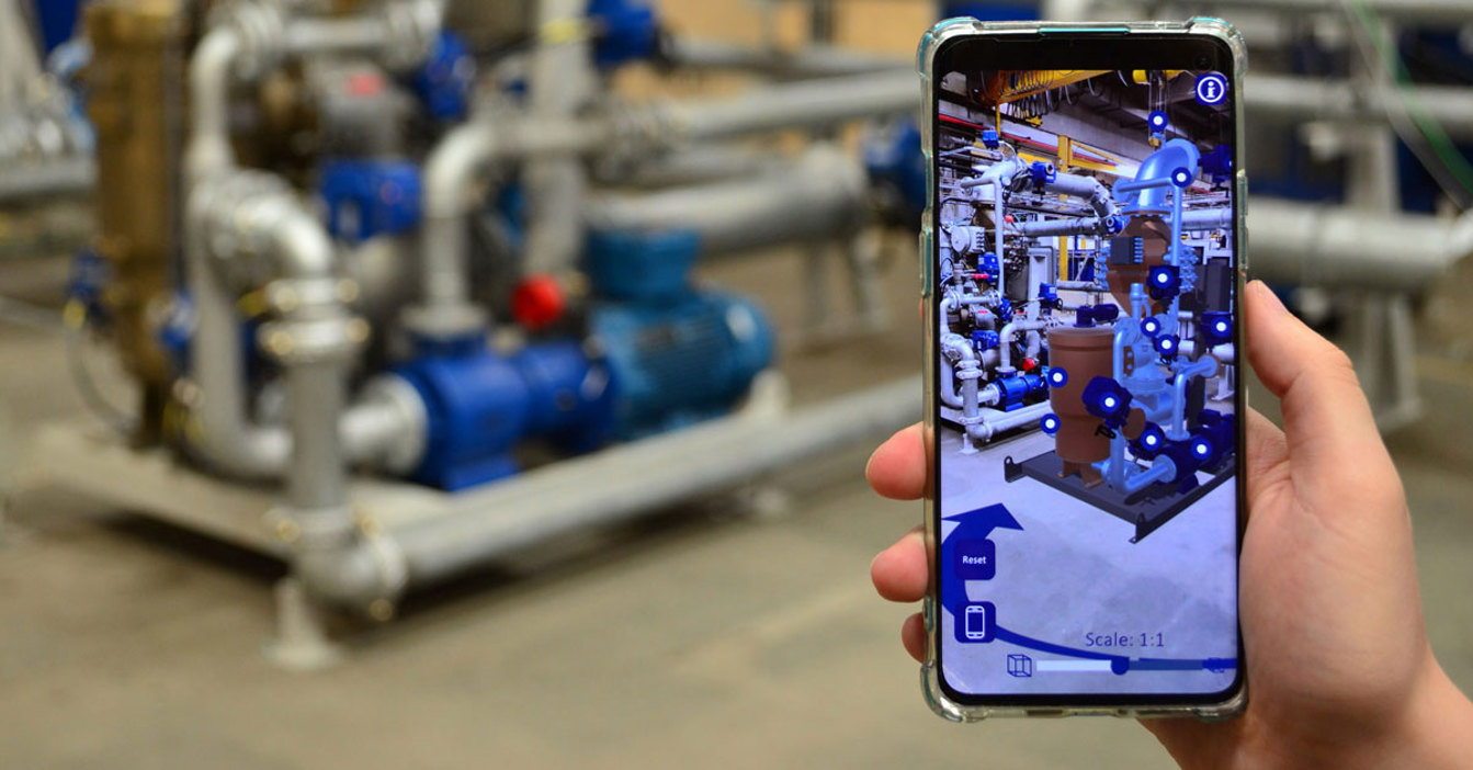 Person using augmented reality app to view industrial equipment layout on smartphone.