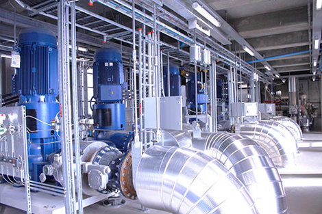 Industrial facility with large blue pumps and metallic pipes for fluid handling.