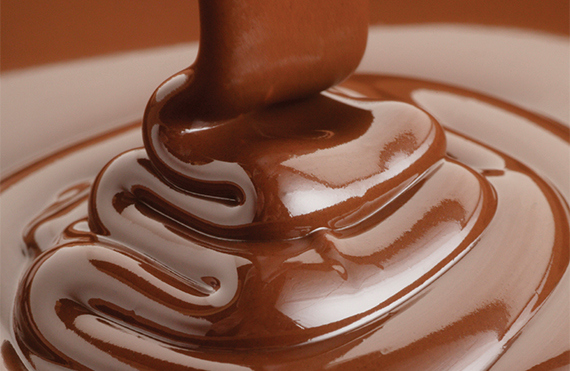 Chocolate suave y brillante siendo vertido en un movimiento en espiral.