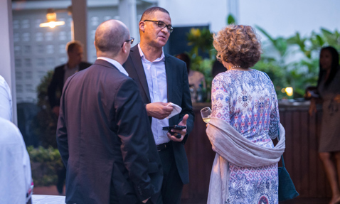 Three people conversing at an outdoor gathering, one holding a drink.