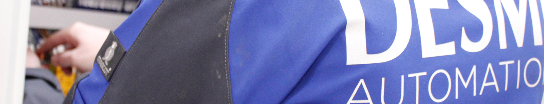 Person wearing a blue DESMI Automation jacket, interacting with equipment.