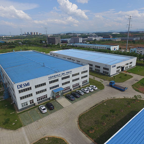 Aerial view of DESMI facility with blue-roofed buildings and surrounding greenery.