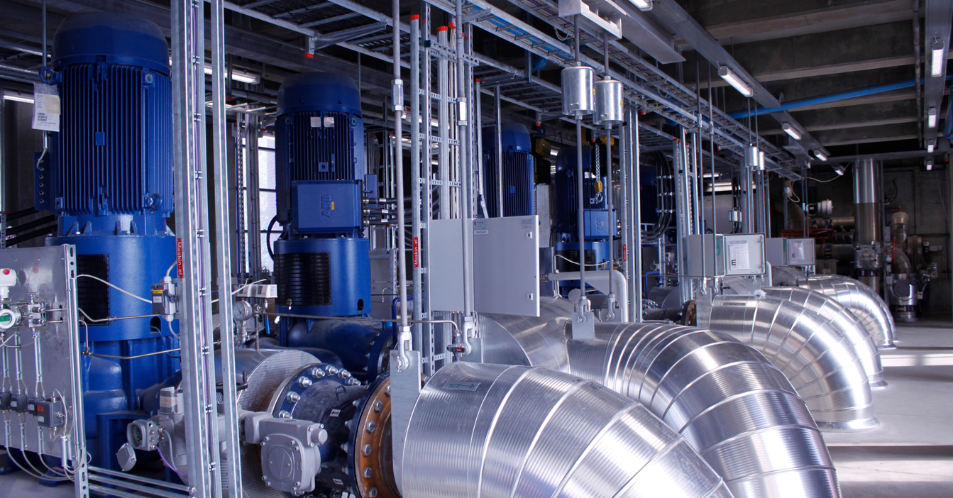 Industrial facility with large blue pumps and metallic ductwork for fluid handling.