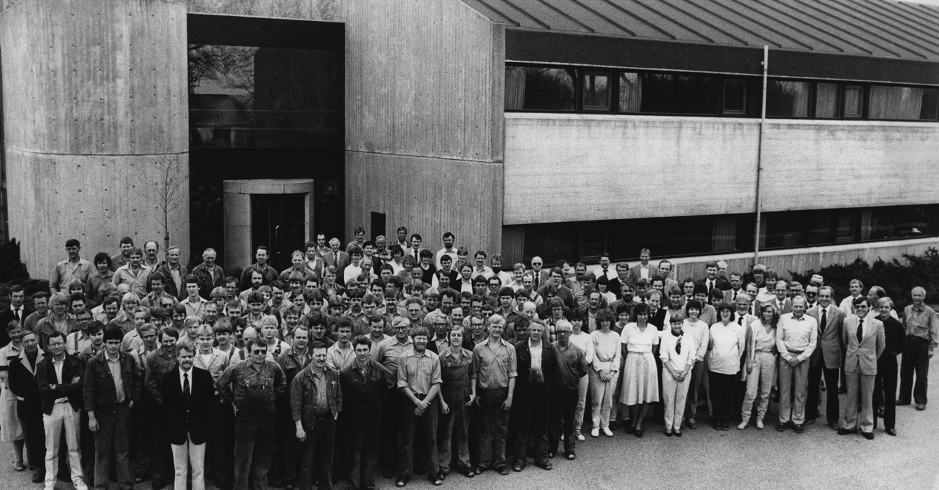 Large group of people gathered in front of a modern building for a photo.