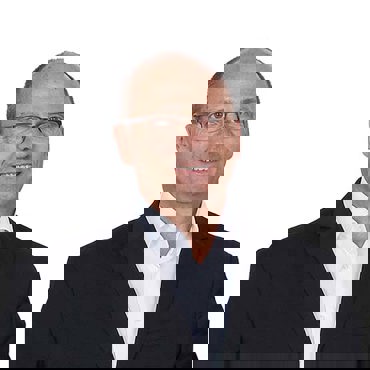 Smiling man in a black suit and white shirt against white background.