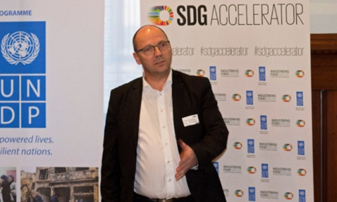 在哥本哈根的UNDP和SDG Accelerator活动中发言的男子，DESMI标志可见。