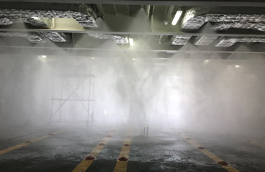 Test av sprinklersystem i en industriell miljö med dimma och ställning.