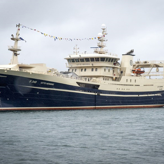 Large fishing vessel docked at a harbor under overcast skies.