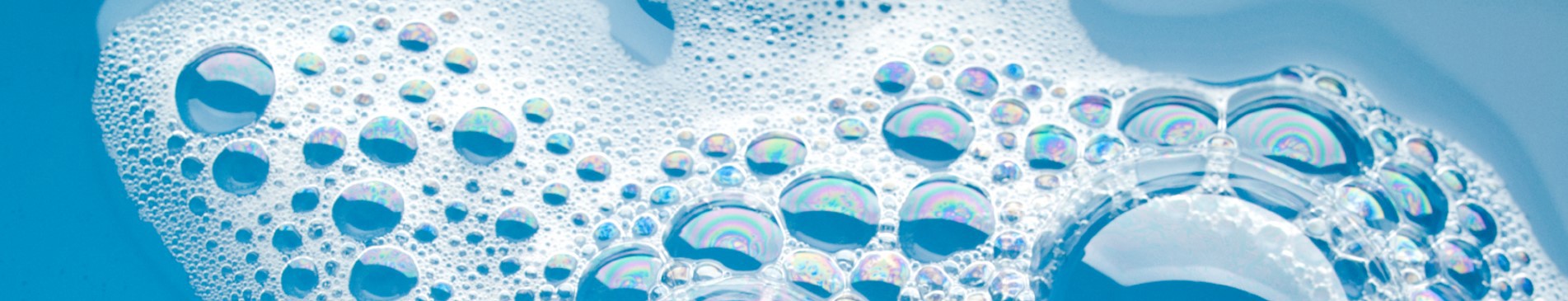 Soap bubbles floating on blue water, displaying iridescent colors.