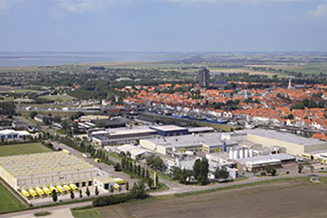 Aerial view of an industrial complex near a town with orange-roofed buildings.