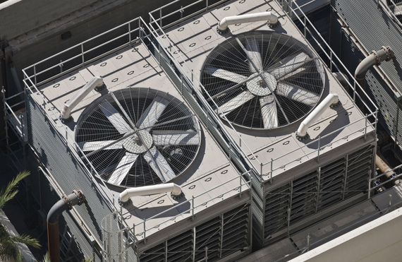 Two large industrial cooling fans on a rooftop, surrounded by safety railings.