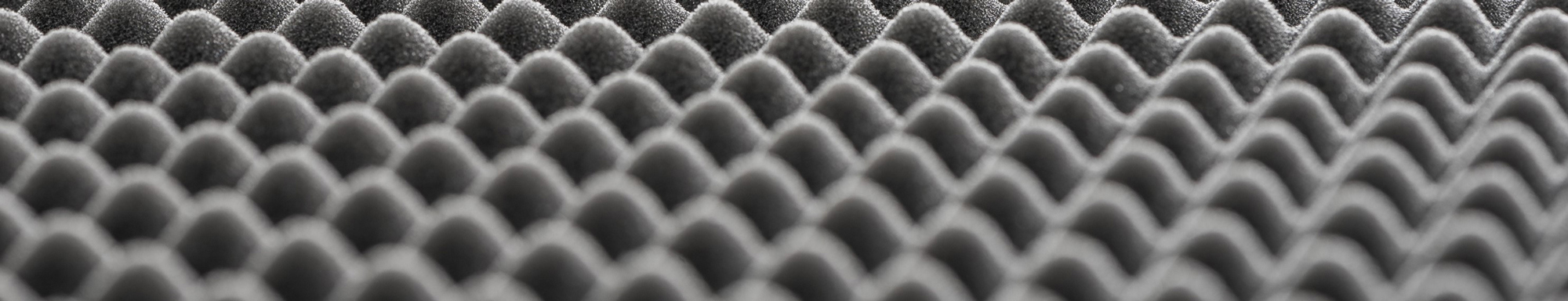 Primo piano di un motivo in schiuma grigia con texture a cassetta per uova, utilizzato per l'insonorizzazione.