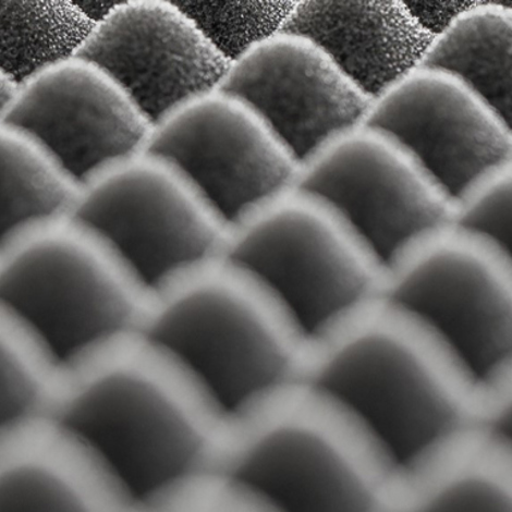 Zbliżenie teksturowanego, szarego wzoru pianki typu egg crate, używanej do dźwiękoszczelności.