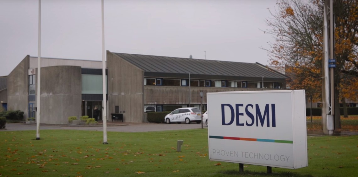 DESMI building with a sign reading "Proven Technology" on a grassy area.