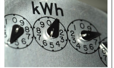 Close-up of analog electricity meter dials displaying kilowatt-hour (kWh) readings.