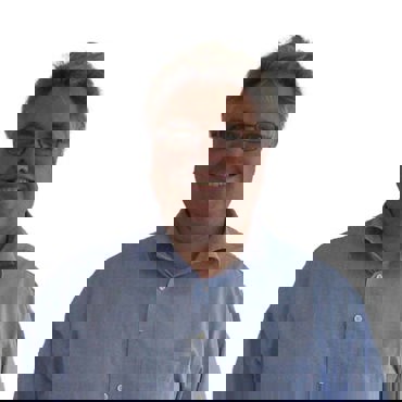 Smiling man in a light blue shirt against a plain white background.