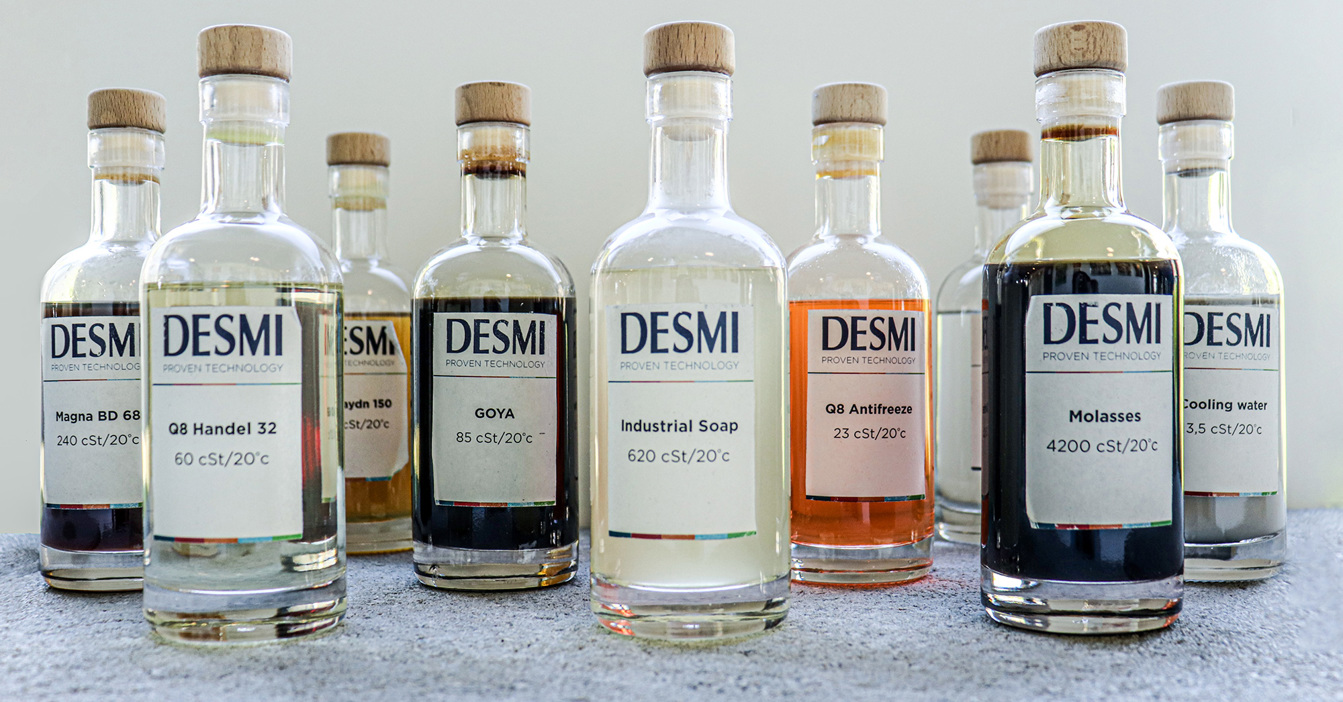Bouteilles de divers lubrifiants et fluides DESMI avec viscosités étiquetées.