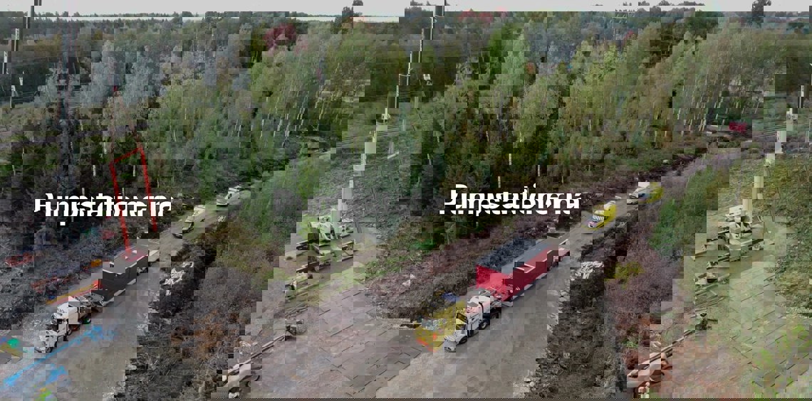 Byggarbetsplats med lastbilar och kran nära skog, märkt "Pumpstationerna."