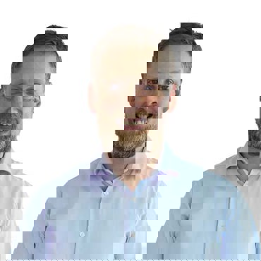 身穿浅蓝色衬衫的微笑男子，背景为纯白色。