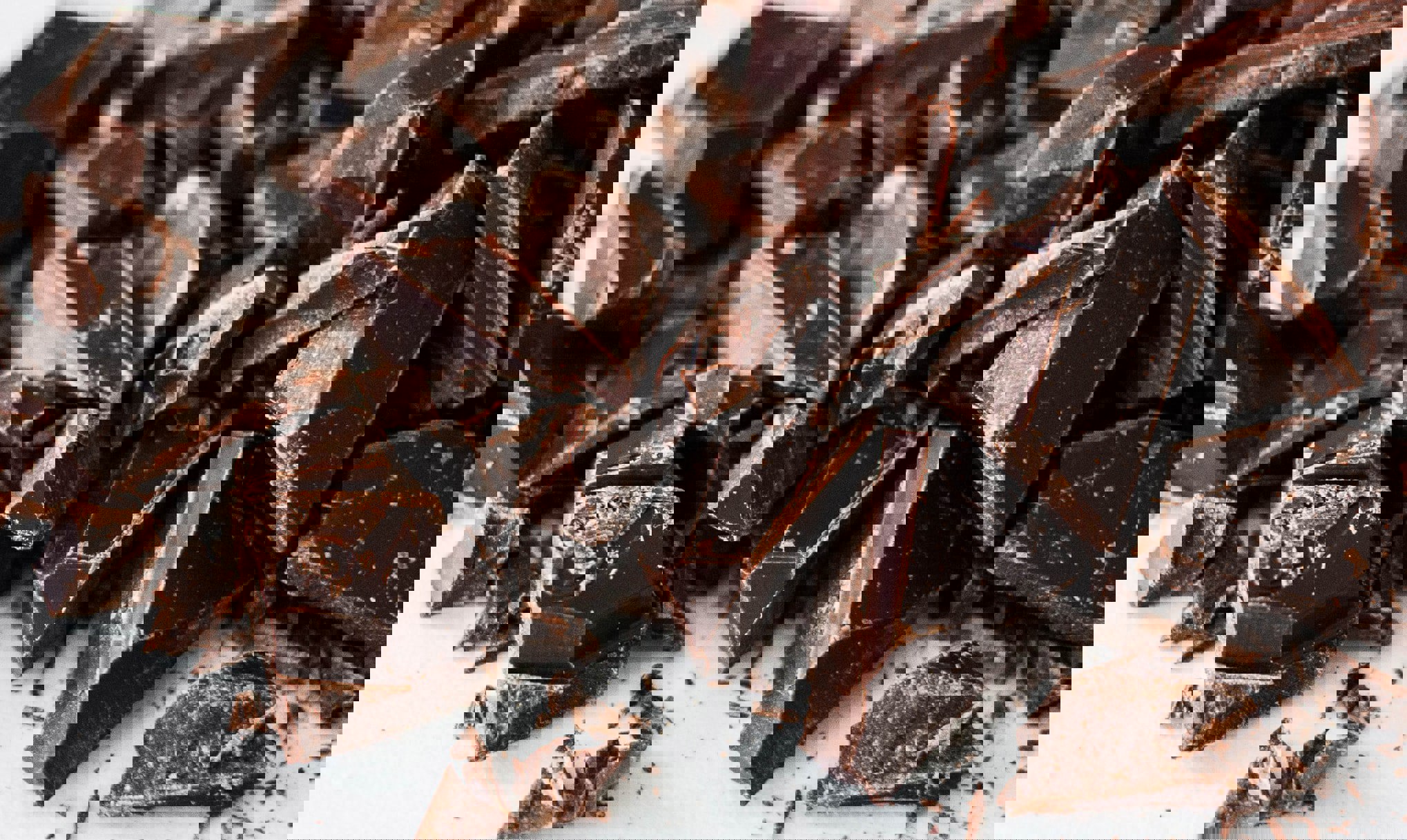 Chopped dark chocolate pieces on a white surface.