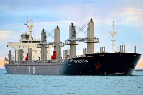 Large cargo ship "IVS Merlion" sailing on calm waters under a cloudy sky.