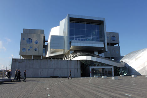 Modern architectural building with circular windows and people walking in foreground.