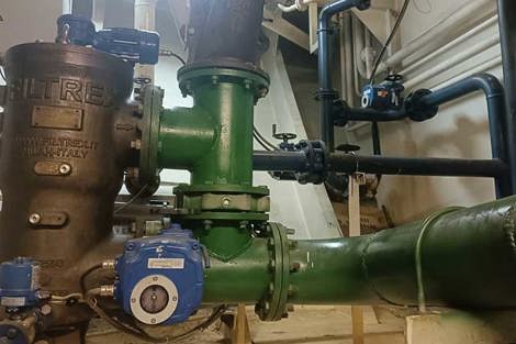 Industrial filtration system with green pipes and control valves in a mechanical room.