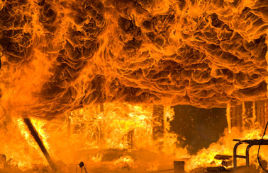 Intensives Feuer verschlingt eine Struktur, mit Flammen und Rauch, die dramatisch wirbeln.