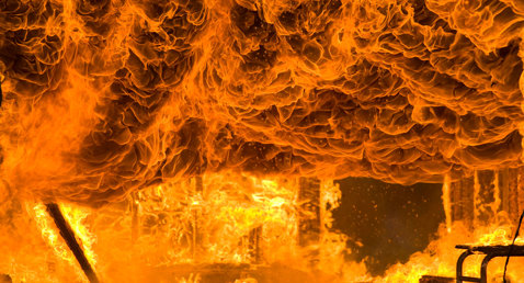 Intense fire engulfing a structure, with flames and smoke swirling dramatically.