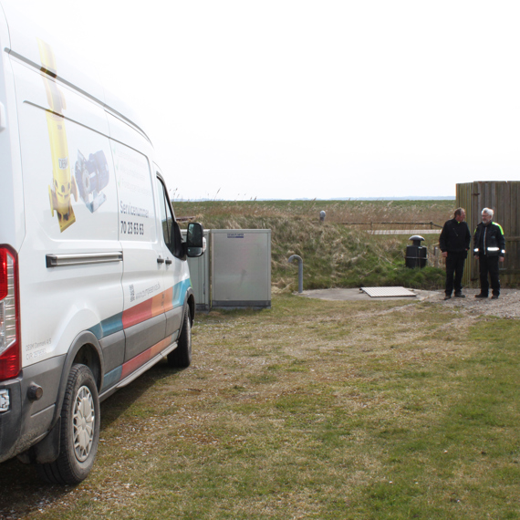 Service van with DESMI branding parked, two people standing nearby outdoors.