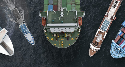 Aerial view of five ships, including cargo and passenger vessels, in the ocean.
