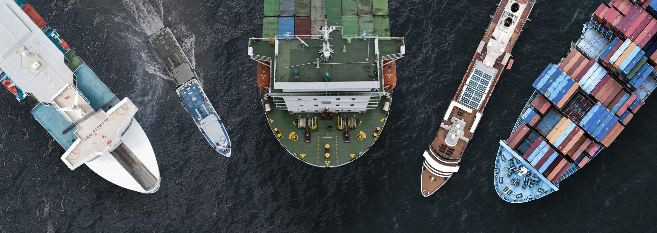Aerial view of five ships, including cargo and passenger vessels, in the ocean.
