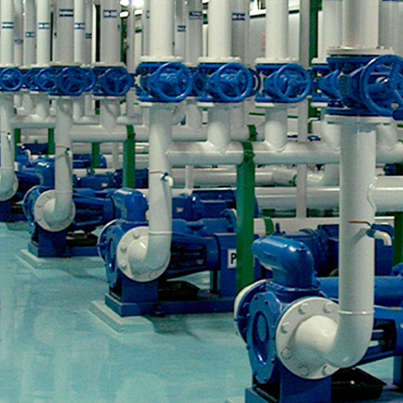 Row of industrial pumps with blue valves and white pipes for fluid handling.