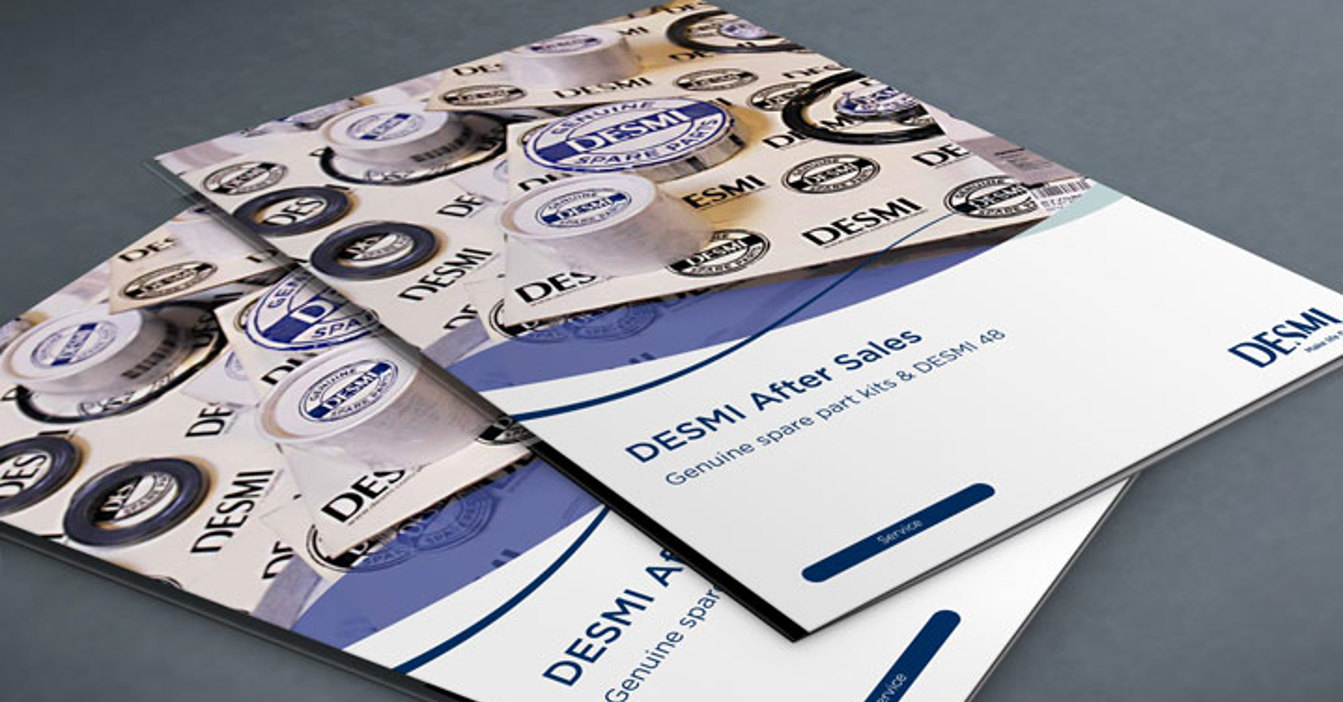 Folletos de postventa de DESMI con el logotipo de la empresa sobre una superficie gris.