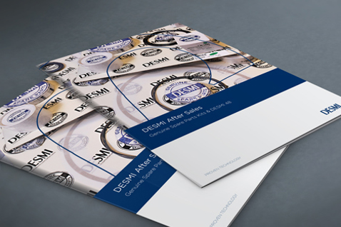 Folletos de postventa de DESMI con el logotipo de la empresa sobre una superficie gris.