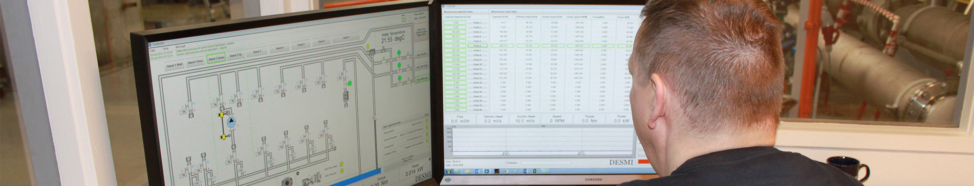 Person monitoring DESMI fluid handling system on dual computer screens.