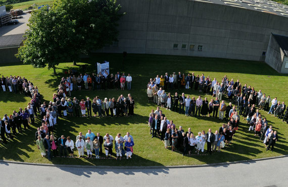 Aerial view of people forming the word "DESMI" on a grassy area.