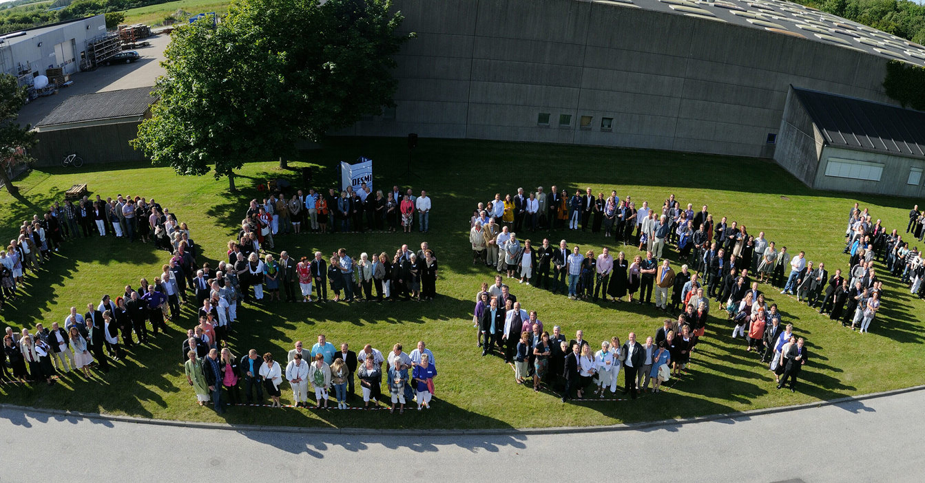 Aerial view of people forming the word "DESMI" on a grassy area.