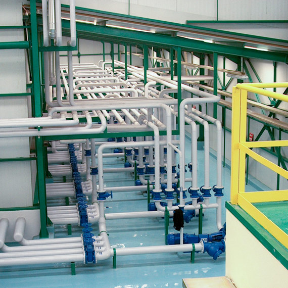 Industrial piping system with multiple white pipes and blue valves in a facility.
