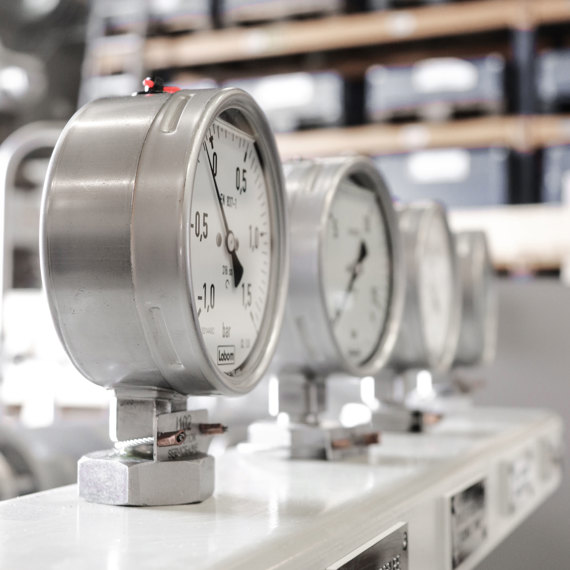 Close-up of industrial pressure gauges in a workshop setting.