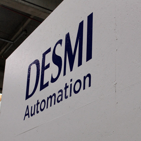 DESMI Automation logo on a white wall in an industrial setting.