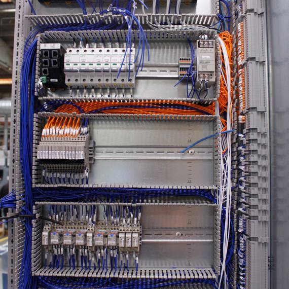 Electrical control panel with organized wiring and circuit breakers in an industrial setting.
