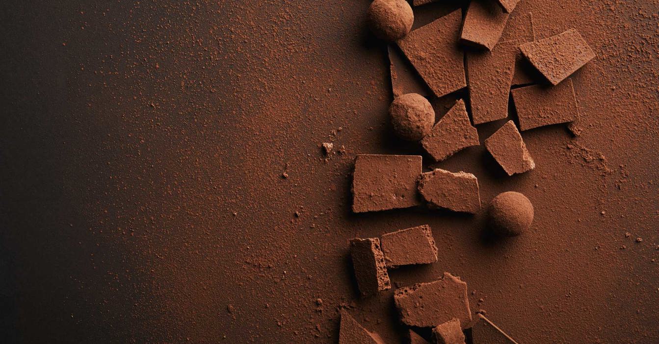 深色背景上的碎巧克力块和撒有可可粉的松露。