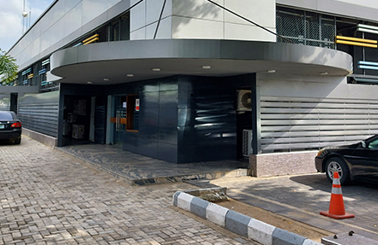 Modern building entrance with sleek design, parked cars, and an orange traffic cone.