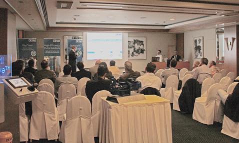 Conference attendees watching DESMI presentation on OptiSave pumping solutions in a meeting room.