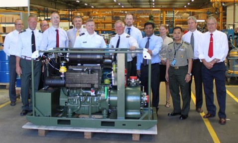 Group of people standing behind industrial machinery in a factory setting.