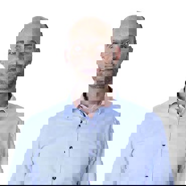 身穿浅蓝色衬衫的男子在纯白色背景前微笑。