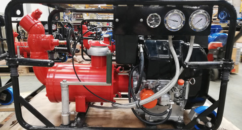 Red industrial pump with gauges, mounted on a black metal frame in a workshop.