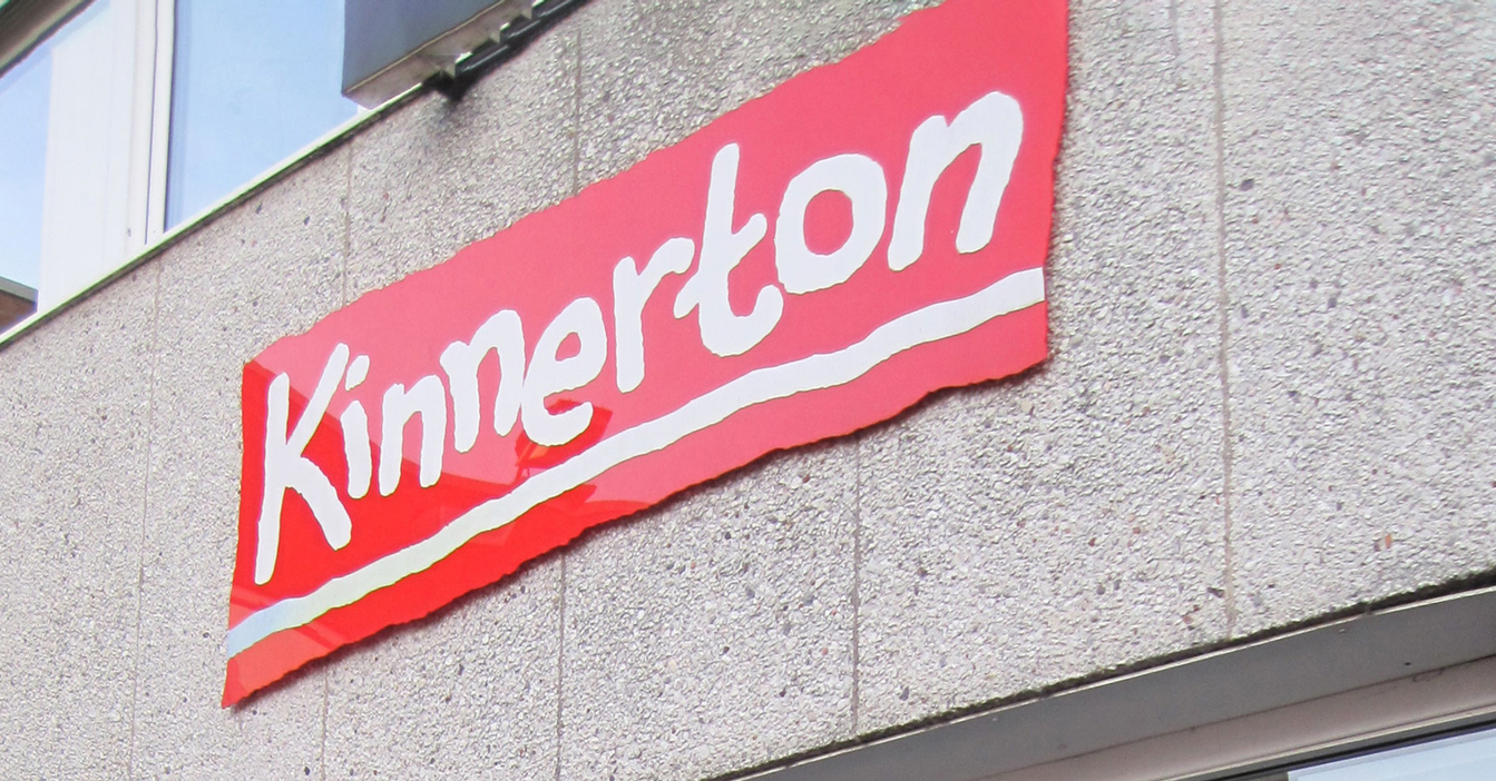 Red Kinnerton sign on a building wall with windows above.