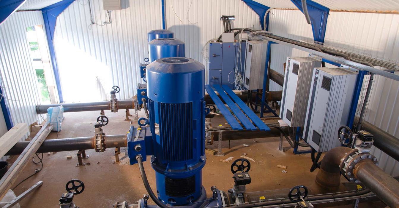 Industrial room with blue DESMI pumps and control panels for fluid handling.